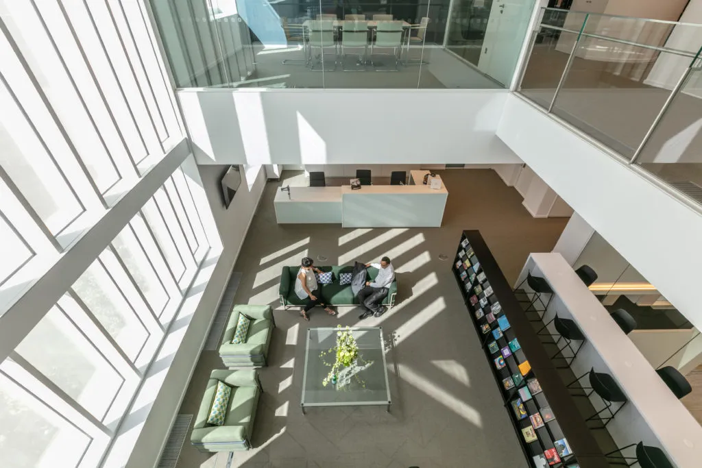 A view looking down from a balcony onto two people sitting on a sofa in the Aga Khan Centre Library.