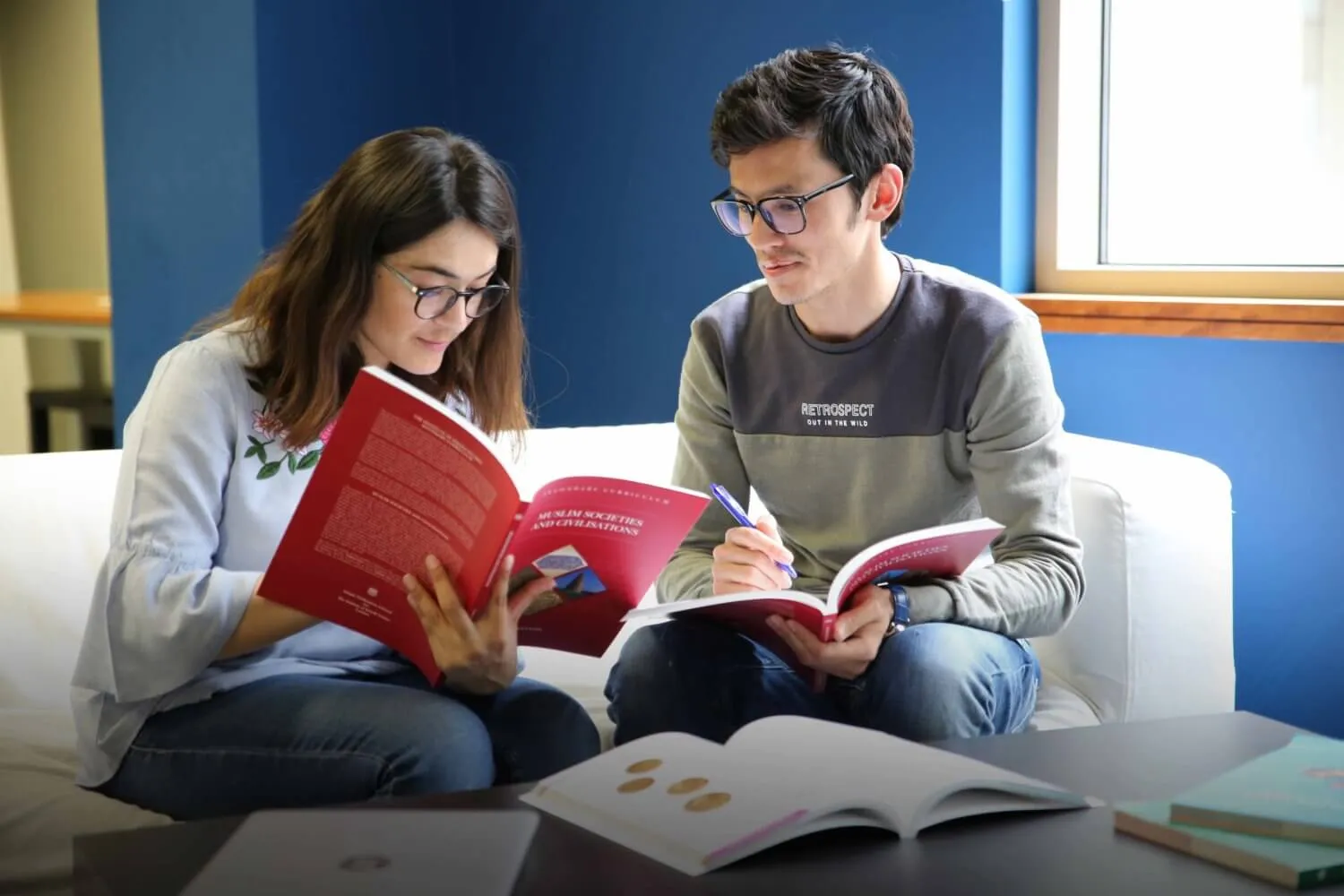 Two students sitting together on a white sofa.