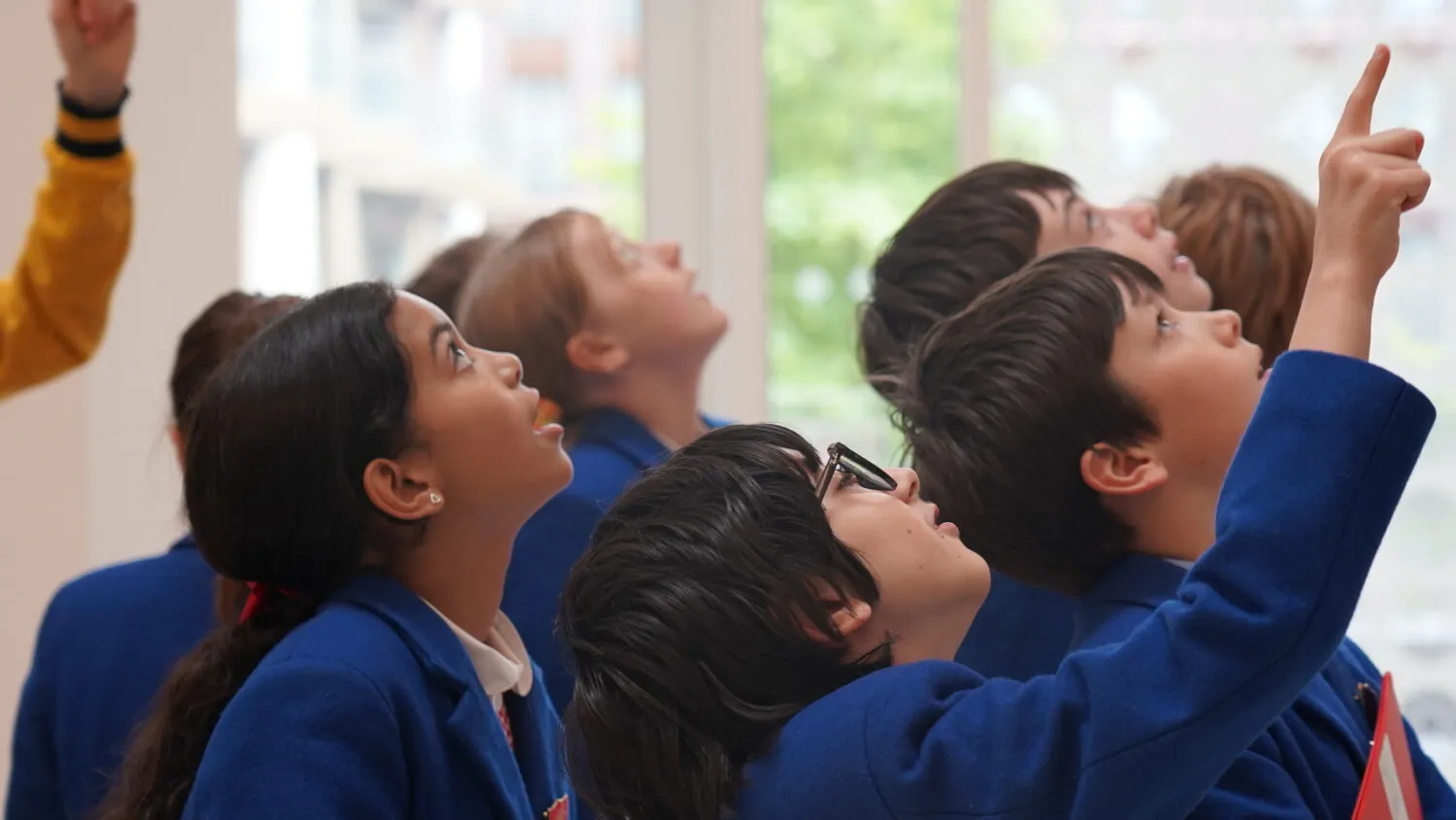 A group of primary school students pointing upwards.