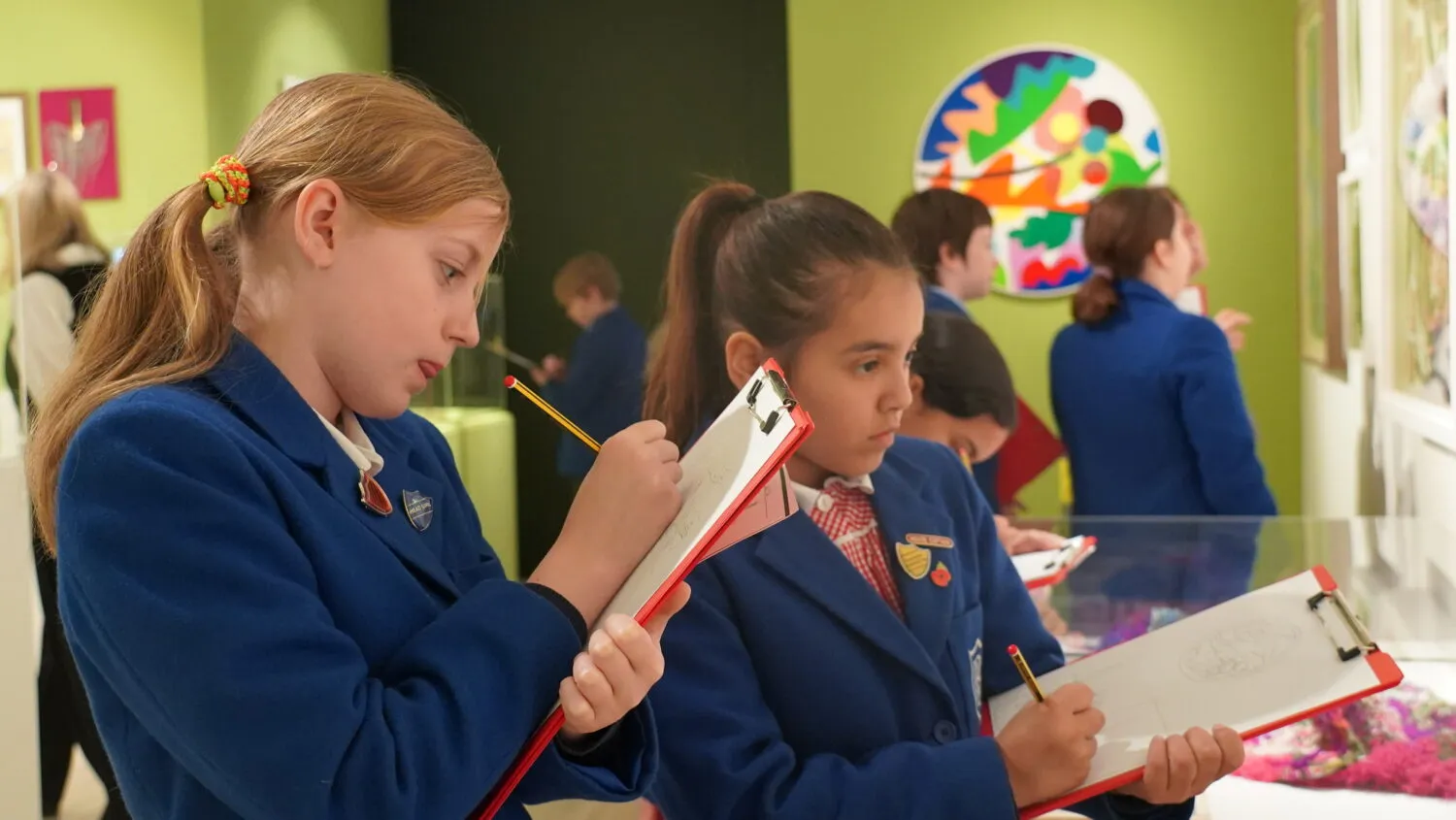 Two primary school students drawing in a colourful gallery.